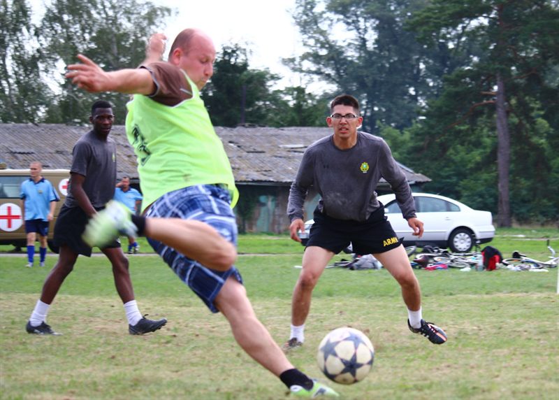 Adults in practice pinnies playing a friendly soccer match on a grass field
